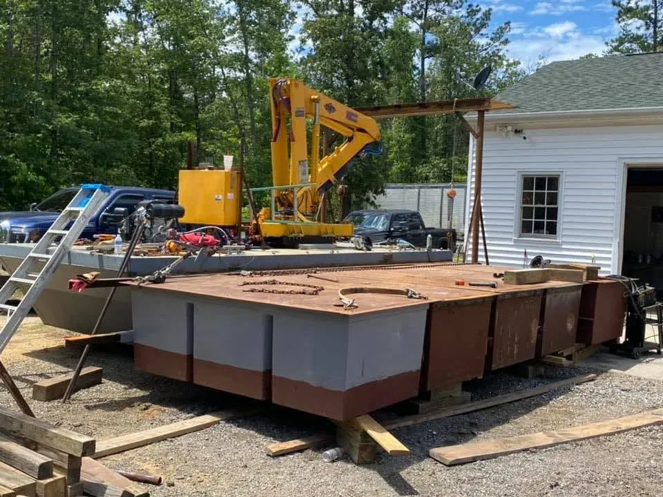 Steel barge sections under construction in the yard beside a crane