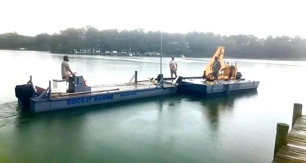 The crew running the barge and a second work float across the water