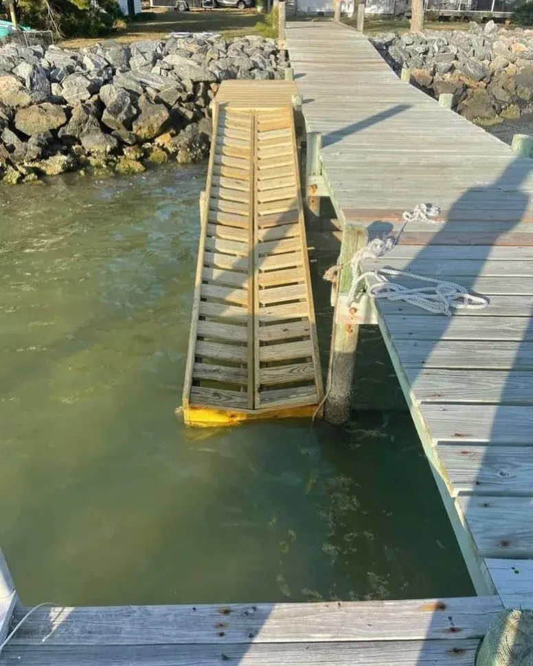 A custom kayak launch ramp alongside a pier, with stone along the bank
