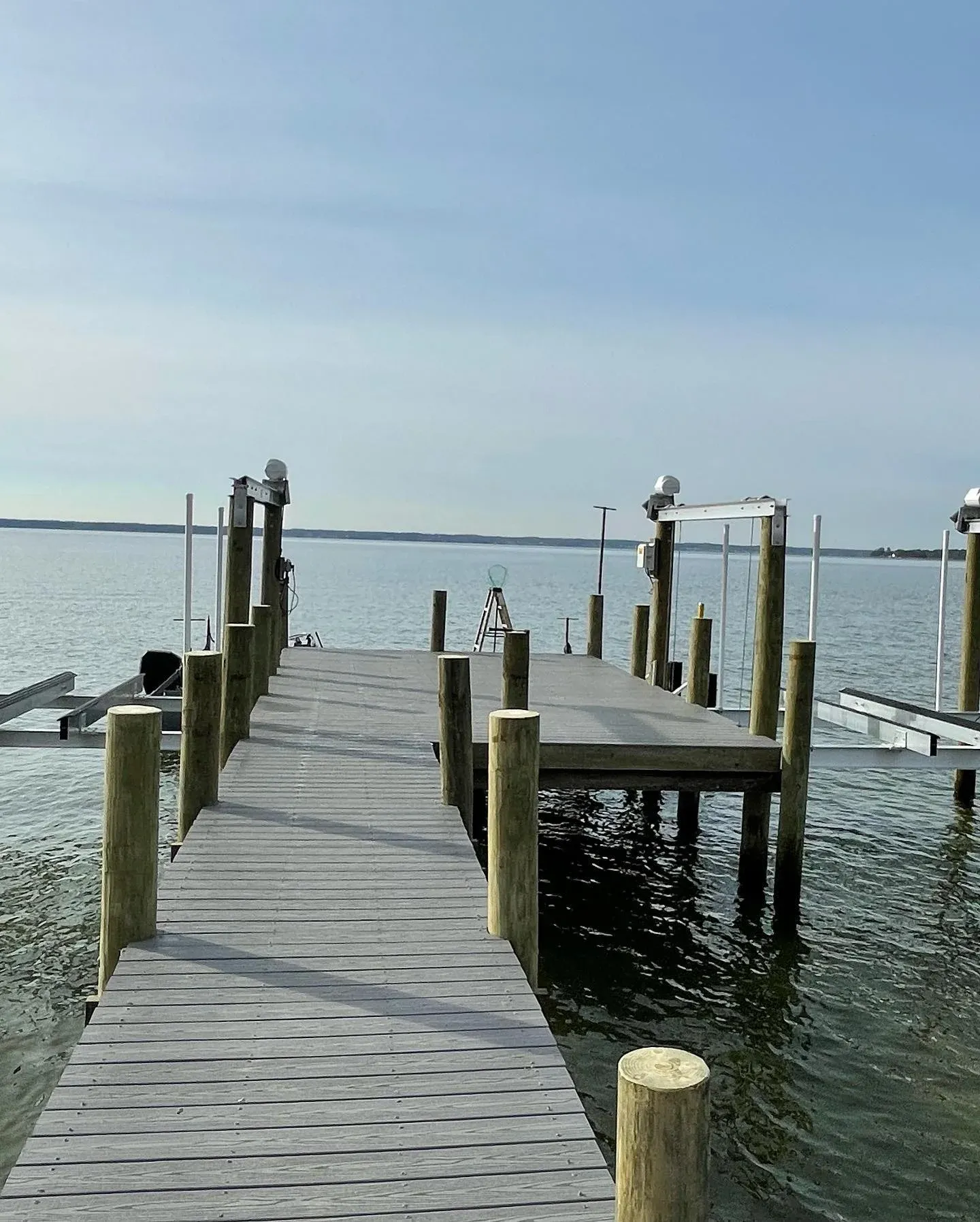 The end of a long pier with a boat lift and pilings