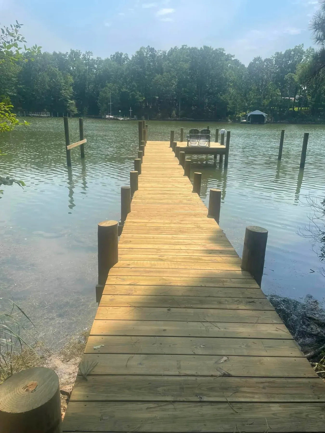 A long new pier running out into a creek between rows of pilings